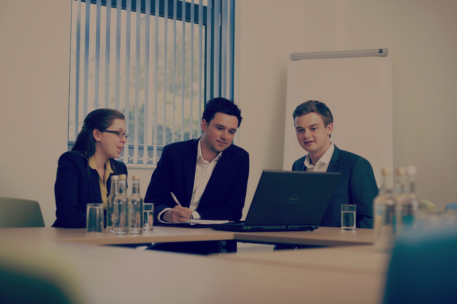 Image of 3 people arround laptop in a conference room at OVIC